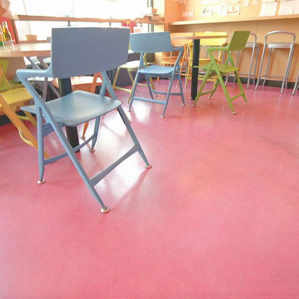 pavimento microcemento fuxia in caffetteria con sedie di diversi colori in primo piano