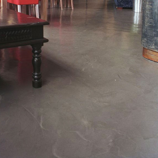 pavimento in microcemento grigio antracite in un lounge bar moderno con sedie rosse