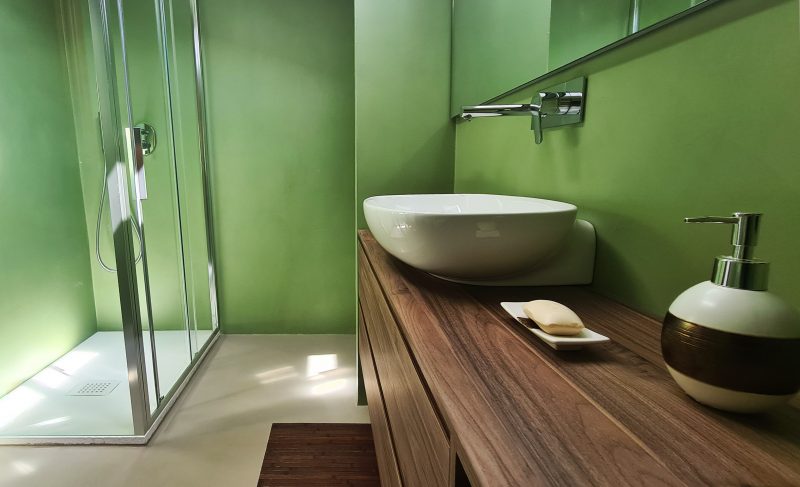 bagno con parete in resina verde e pavimento in resina grigia